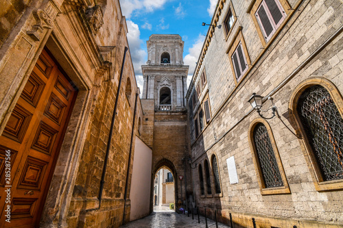 A medieval bell tower with a tunnel opens up to the ancient Piazza del duomo in the historic center of Brindisi Italy.