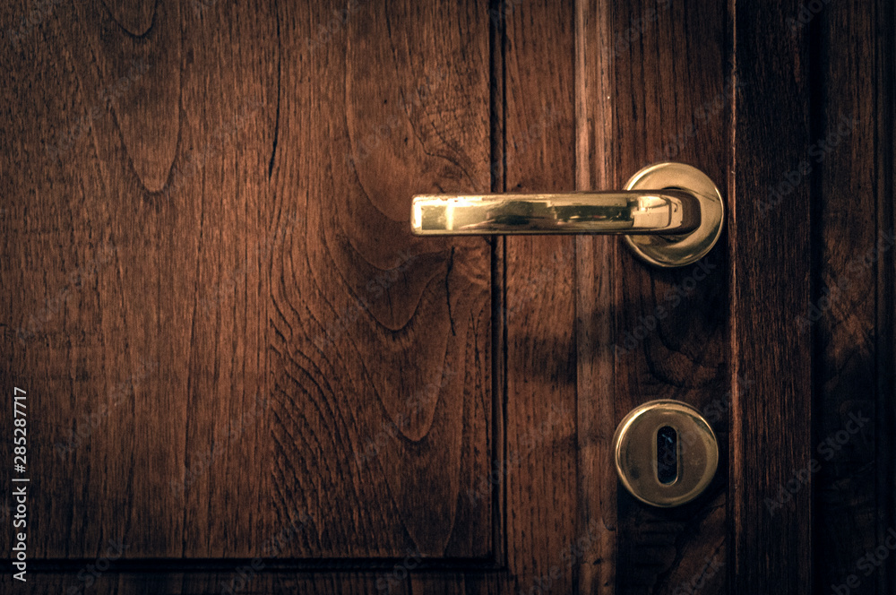 An old wooden door with golden handle sorrounded by black vignette An old wooden door with golden handle sorrounded by black vignette