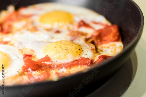 Fried eggs with onions, tomato and pepper, cooking in a pan, breakfast, healthy lifestyle