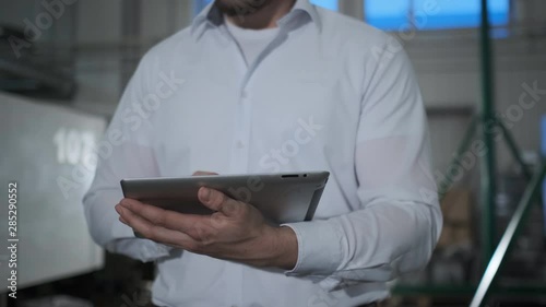 Engineer in hardhat is moving through a heavy industry factory with a tablet computer. Slow-Motion. 4k. Close-up