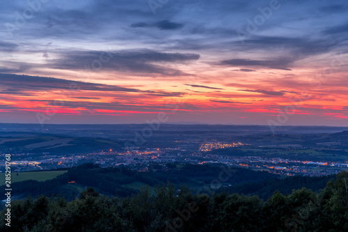 The setting sunset over the town of Valasske Mezirici as the city and its surroundings public light up slowly multi colored dark clouds and sun hiding below horizon.