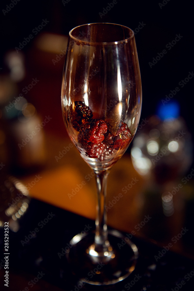 Blackberry in a glass with champagne in the interiors of the bar. Making a cocktail. Blackberry in a glass with champagne in the interiors of the bar. Making a cocktail.