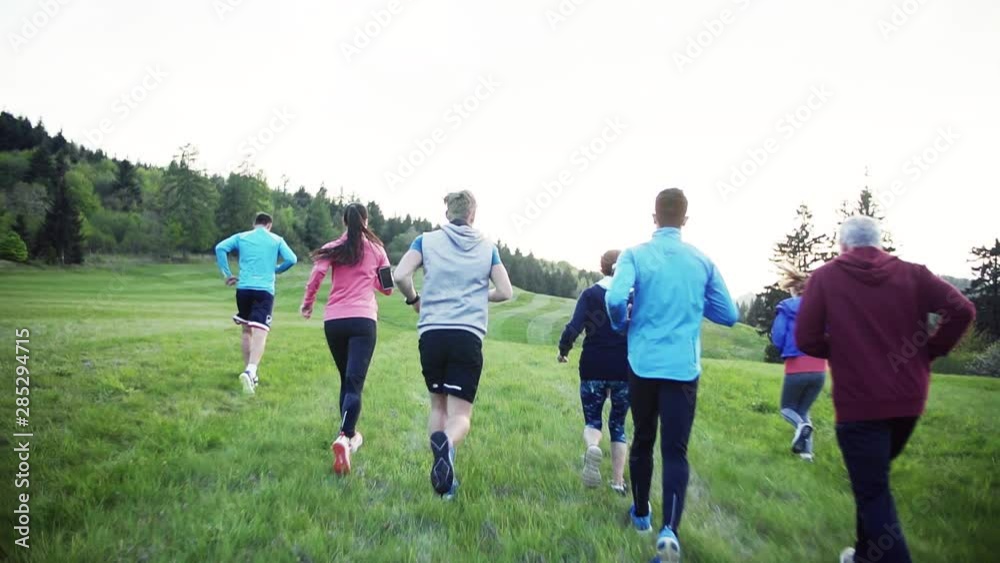 Rear view of large group of people cross country running in nature. Rear view of large group of people cross country running in nature.