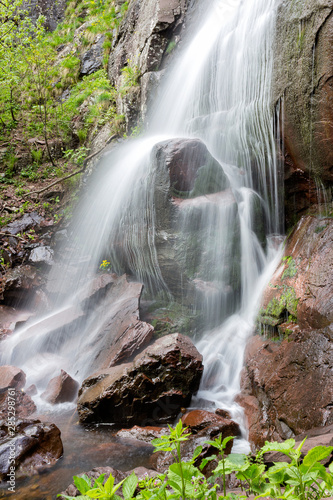 Blur motion capture of waterfall  called Chungulj and yellow flower behind the silky water stream curtain