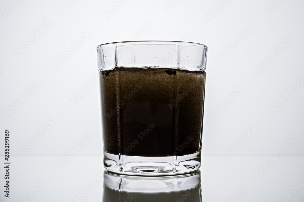 Close-up of glass Cup with dark contaminated water Close-up of glass Cup with dark contaminated water