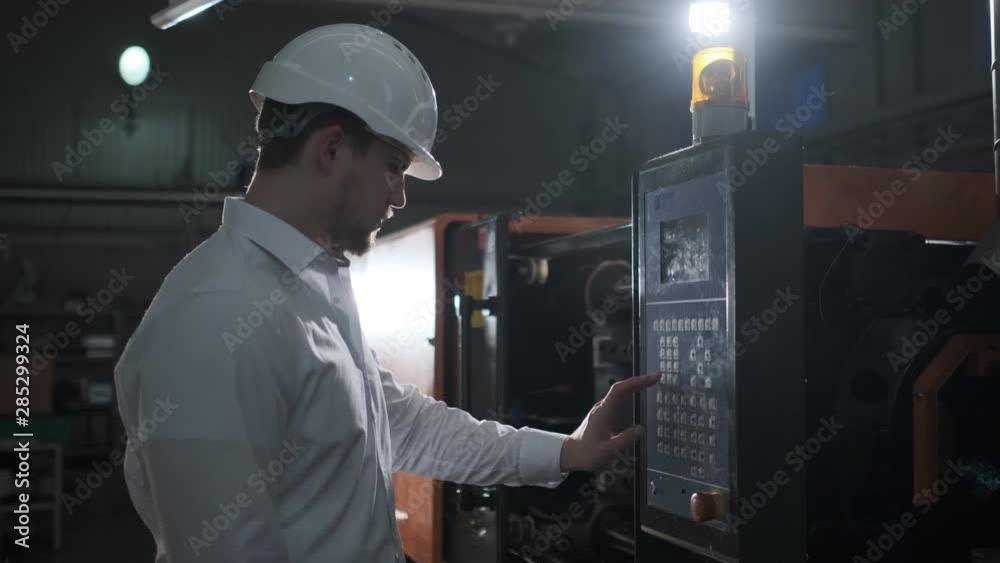 Engineer in a white helmet checks the condition of the Metalworking machine. 4k