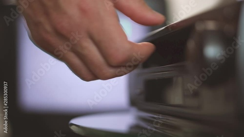 A man pulls out a video cassette from a VCR. Hand close-up. Black VCR near an old TV photo