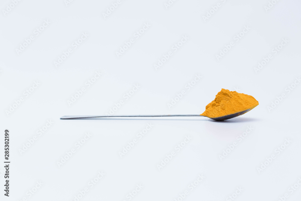 Turmeric powder in the spoon isolated on white background