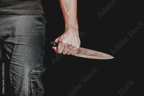 hand with a knife on a black background, maniac,murderer, robber