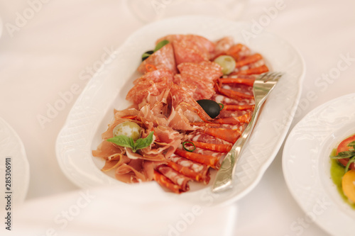 Appetizer in restaurant. Banquet concept. cold meat plate with prosciutto, slices ham, salami, decorated with olive