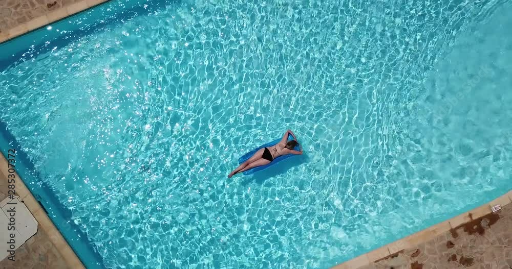 frau im bikini treibt auf luftmatratze in pool