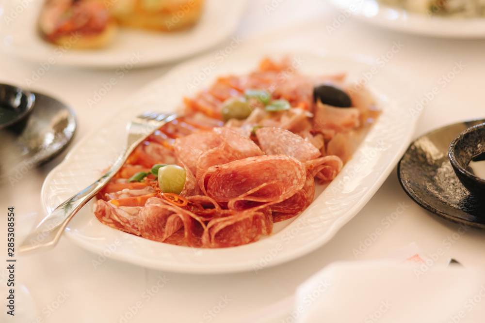 Appetizer in restaurant. Banquet concept. cold meat plate with prosciutto, slices ham, salami, decorated with olive
