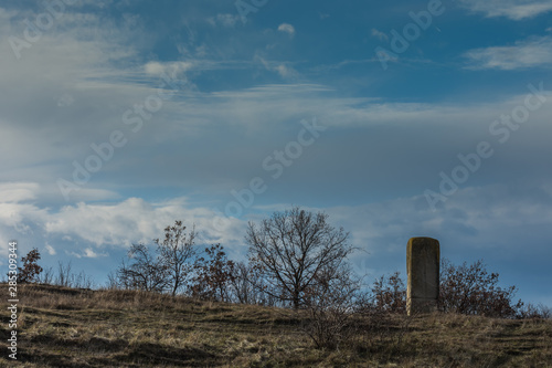 skulptur aus stein in der natur mit wolken am blauen himmel © thomaseder