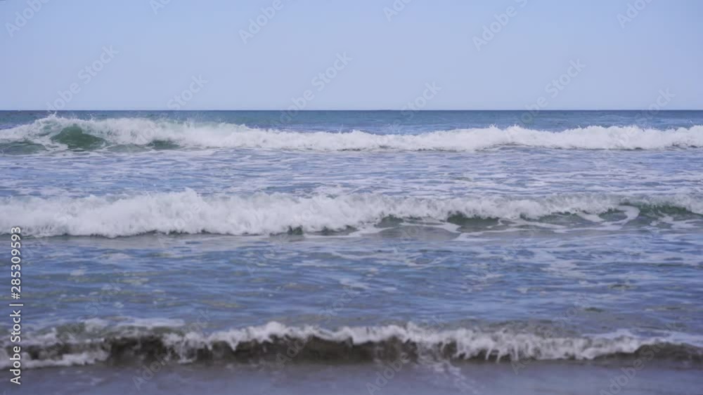 Turquoise blue sea waves splashing at beach in Sicily