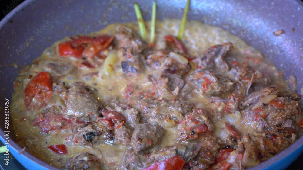 Frying pan with onion, lemongrass, red pepper and beef meat, close up. Indonesia. Sambal Goreng Ati Kentang, Indonesian cuisine, spicy beef meet and potatoes garnish with lemongrass leaf and red chili Frying pan with onion, lemongrass, red pepper and beef meat, close up. Indonesia. Sambal Goreng Ati Kentang, Indonesian cuisine, spicy beef meet and potatoes garnish with lemongrass leaf and red chili