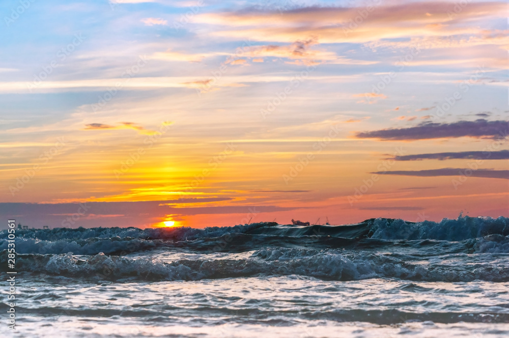 Fototapeta premium Sunset over the sea. Reflection of sunlight in the sea waves. The sky in the sunset rays.