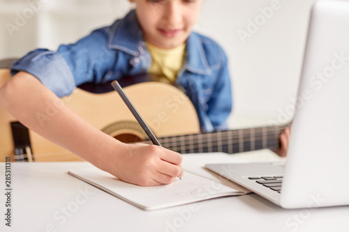 Girl making notes during guitar lesson