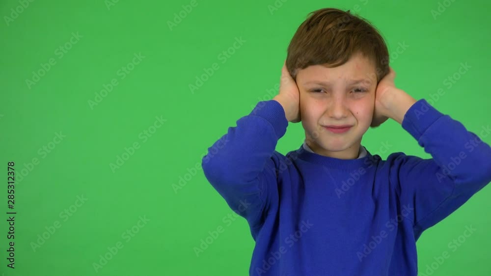 Vidéo Stock A young cute boy hears a piercing noise, frowns and covers