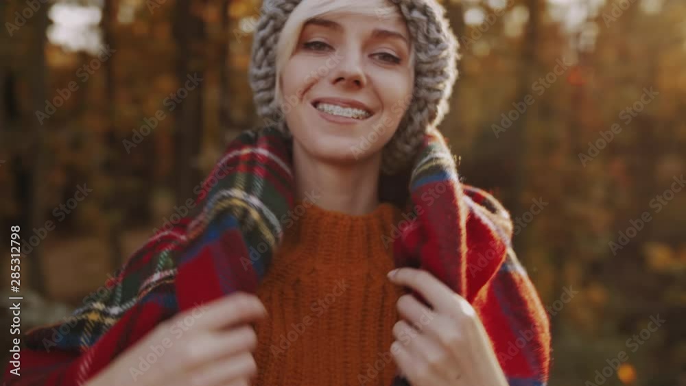 Young happy smiling tourist girl with orthodontic braces on her teeth, wears, wraps in red tartan scarf, enjoys sunny autumn in forest, park Young happy smiling tourist girl with orthodontic braces on her teeth, wears, wraps in red tartan scarf, enjoys sunny autumn in forest, park