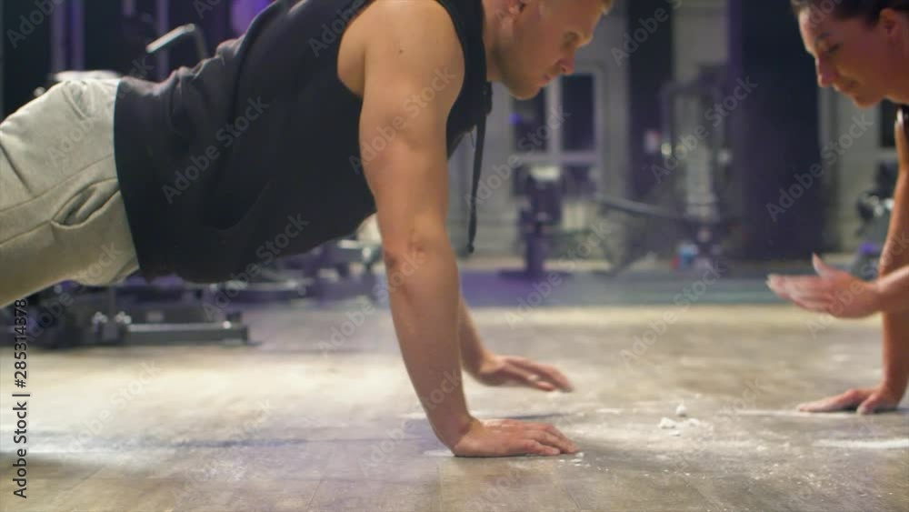 Two athletes doing push ups face to face and clapping hands. Athletic training in gym. Fitness, sport, exercising, training concept.