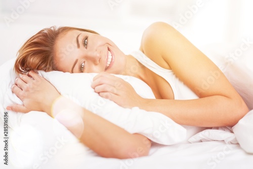 Young woman wakeup after sleeping on the white linen in bed at home