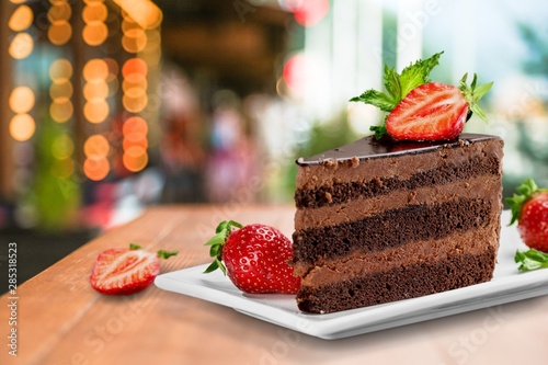 Slice of delicious chocolate cake on desk