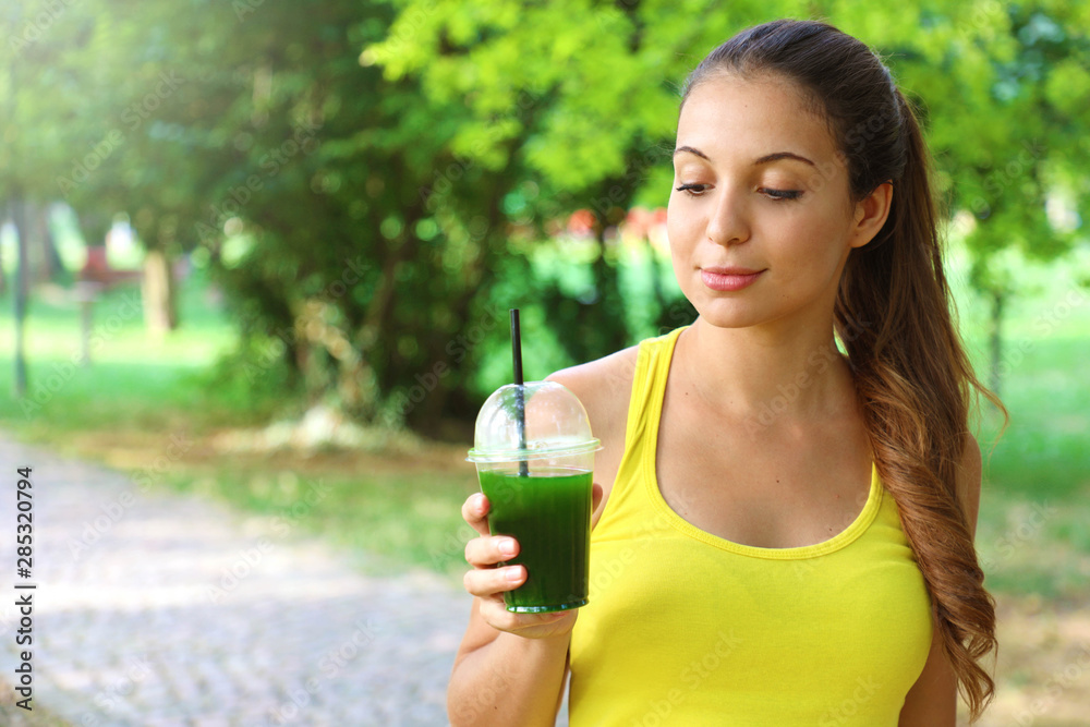 Sporty woman looking at her green detox smoothie with copy space. Sporty woman looking at her green detox smoothie with copy space.