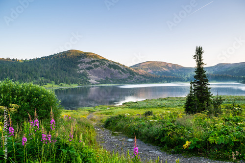 View on mountain lake with hills and green forest during sunrise. Ergaki national park, Siberia, Russia photo