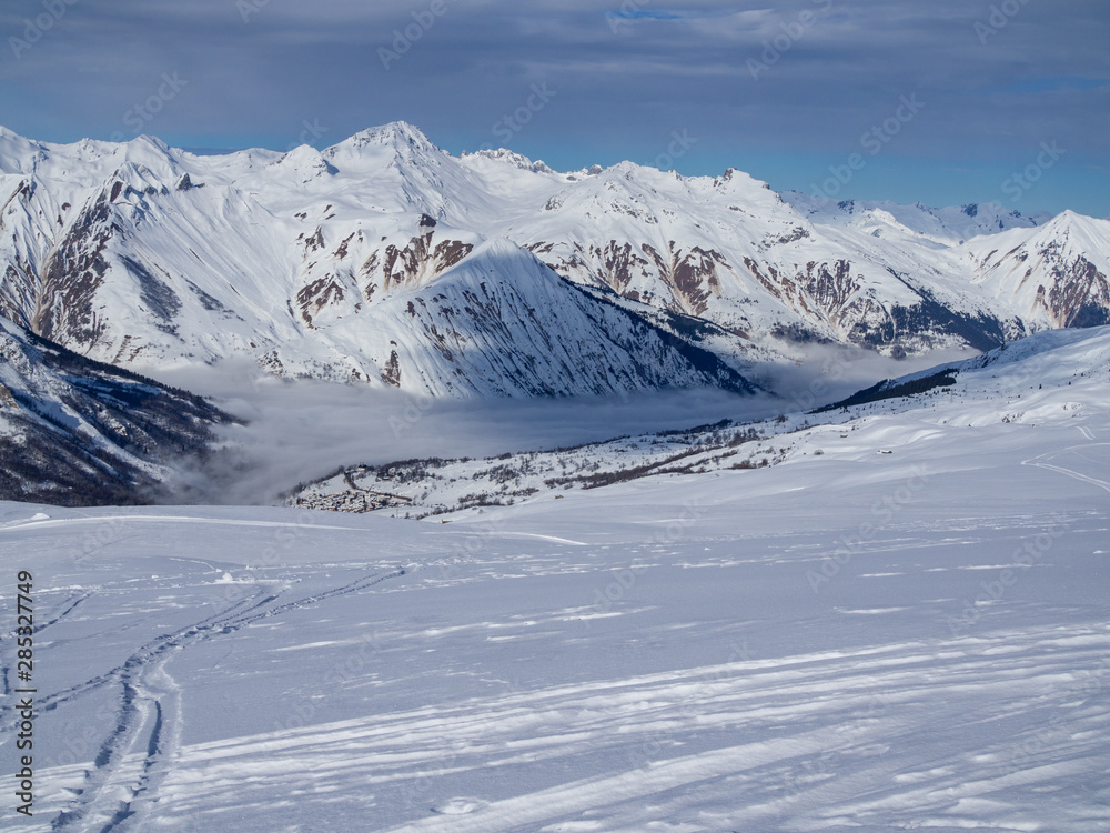 France, Meribel valley: Panoramic landscape view down valley with ski slope piste in winter alpine mountain resort