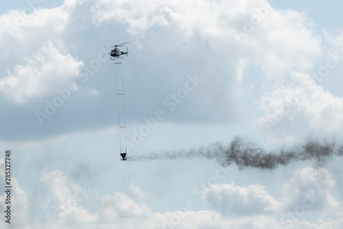 helicpter flying with big barrel of lime over a forest