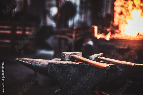 фотографія Dark stithy workshop with hammer on anvil at firs plan and fire in stove at background