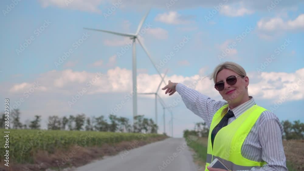 Female engineer in an orange vest and tie controls the operation of wind generators. Energy of the future. Environmental Safety