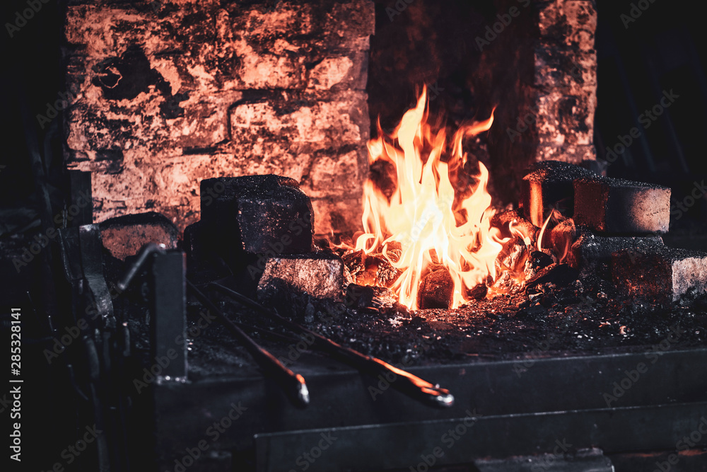 Fototapeta premium Stove with fire at blacksmith workshop. There are different tools around.