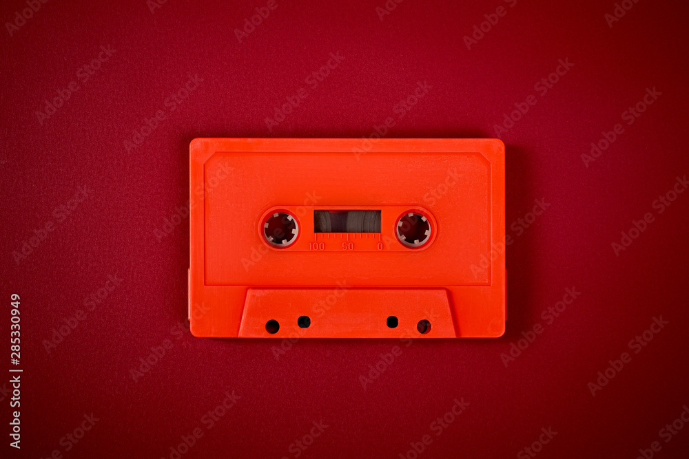 orange audio cassette on the dark red background