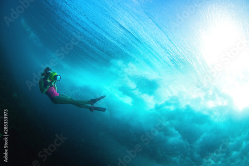 Surf Photographer with the camera dives under a big wave photo