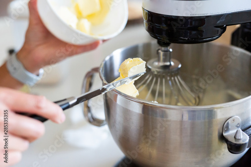 adding butter into bowl of stand mixer, mixing buttercream icing