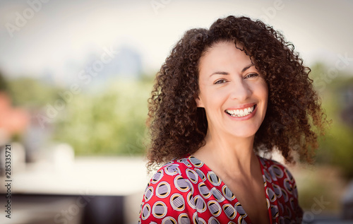 Mature Ethnic Woman Smiling At The Camera. She is outside on the roof of her house