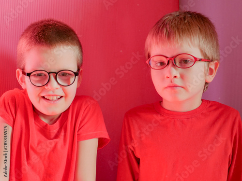 Funny children in red clothes posing in front of camera. Boys actively express their emotions. Preschoolers are happy together at home on vacation
