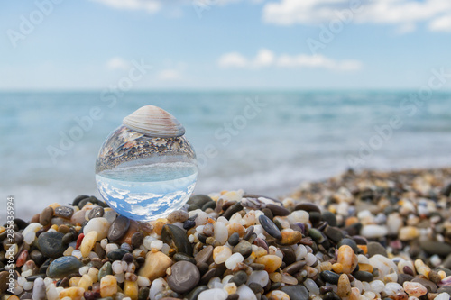 Glass round ball on the beach reflects the sea in summer