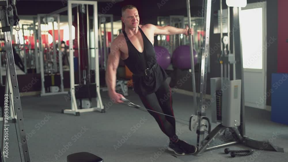 Strong muscular man using exercise machine at the gym. Bodybuilding and fitness concept Strong muscular man using exercise machine at the gym. Bodybuilding and fitness concept
