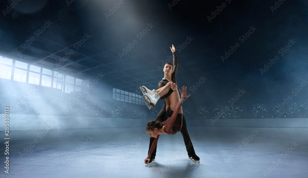 Figure skating couple in professional ice arena.