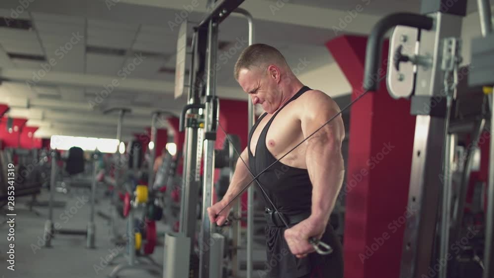 Strong man using a cross cable training machine in gym. Fitness lifestyle Strong man using a cross cable training machine in gym. Fitness lifestyle
