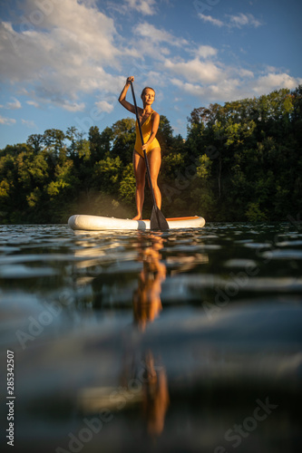 Photography SUP Stand up paddle board concept - Pretty, young woman paddle boarding on a lov