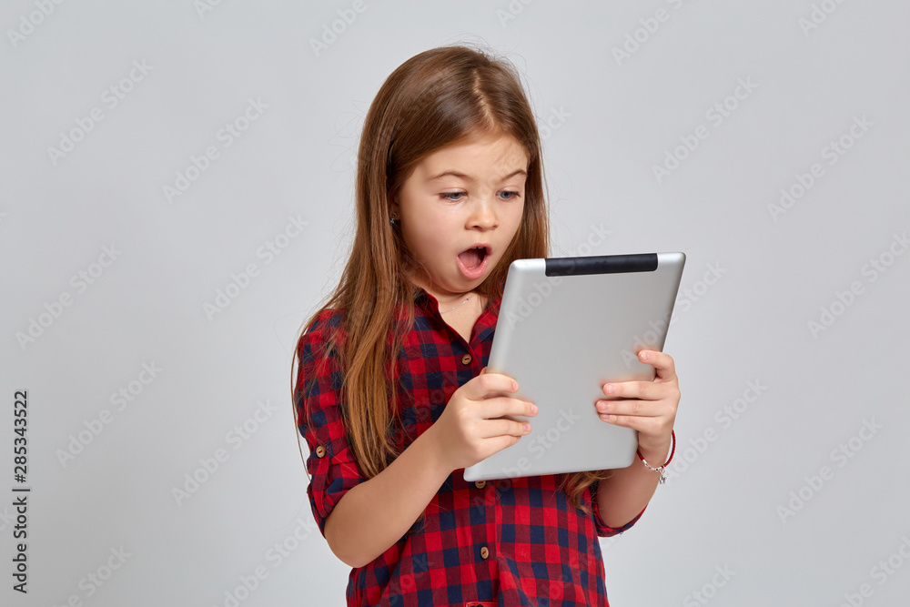 Teenage girl with emotional facial expression. Beautiful female half-length portrait on light background. Teenager with a tablet in his hands Teenage girl with emotional facial expression. Beautiful female half-length portrait on light background. Teenager with a tablet in his hands