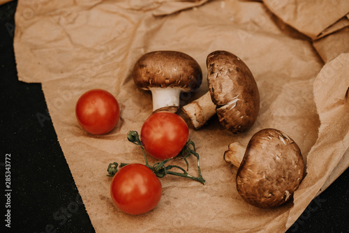 Champignons mushrooms and cherry tomatoes on black background