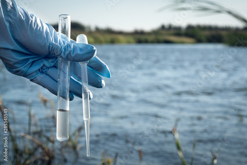 Water pollution concept. Woman scientist takes a water sample from polluted pond.