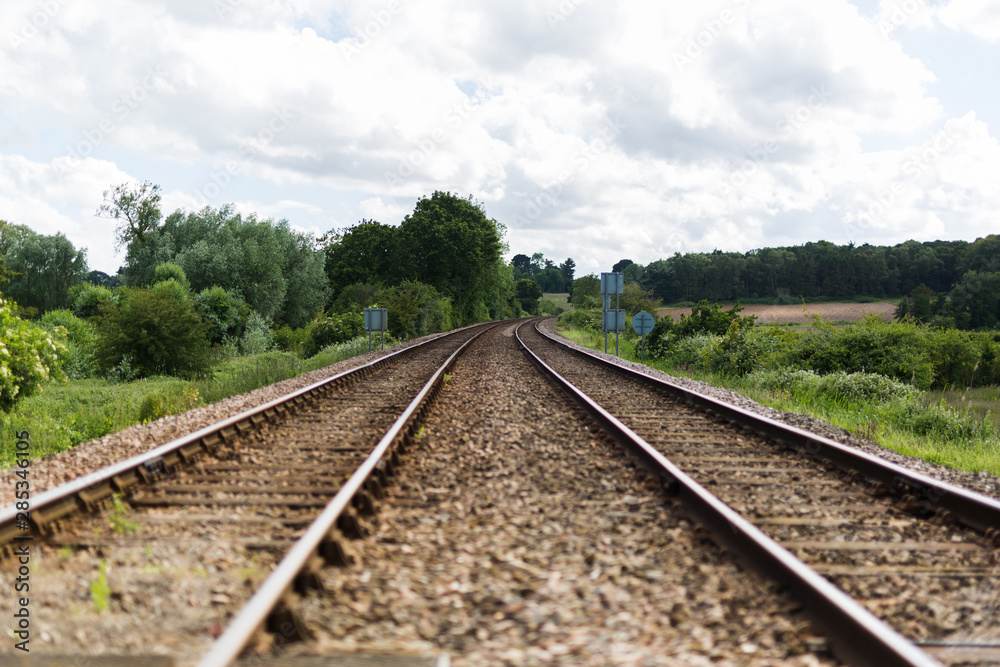 An empty train track, there are 2 tracks leading to a vanishing point on the horizon in rural countryside An empty train track, there are 2 tracks leading to a vanishing point on the horizon in rural countryside
