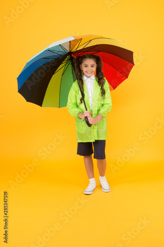Rain is not so bad if you have water resistant clothes. Carefree schoolgirl colorful umbrella wear waterproof rain coat. Autumn rain. Going to school rainy days more fun with bright accessories