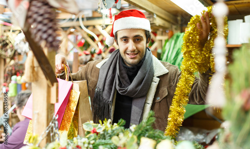 Young man in Christmas hat buying decoration at Christmas Fair outside