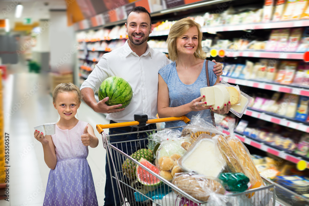 Young parents with girl shopping in hypermarket